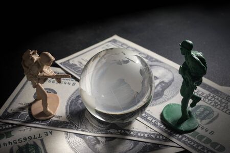 Soldier toys and glass globe on money ,war concept.の写真素材