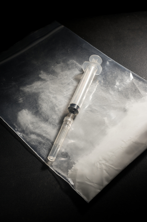 Syringe on cocaine or heroine powder bag,drug concept.の写真素材