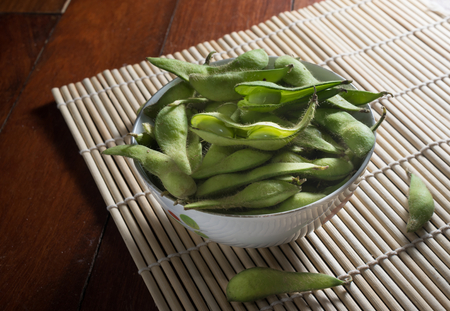 Green soy beans in bowl on bamboo mat.の写真素材