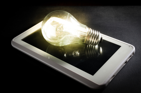Light bulb on computer tablet,concept idea.の写真素材