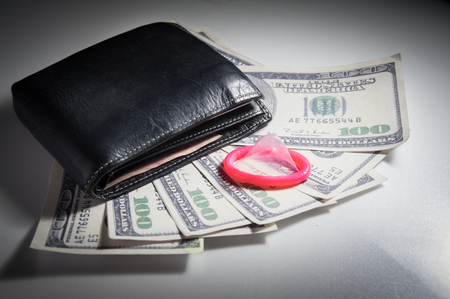 Pink Condom and billfold on money.の写真素材