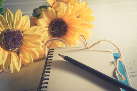 Book with sun flowers on wood table,vintage filtered.の写真素材