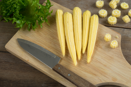 Baby corns and knife on cutting board.の写真素材