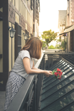 Sad girl hold rose flowers and standing outdoor.の写真素材