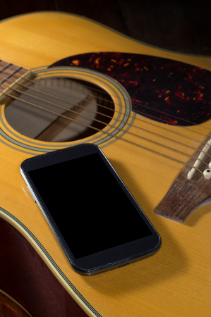 Smart phone on acoustic guitar.の写真素材