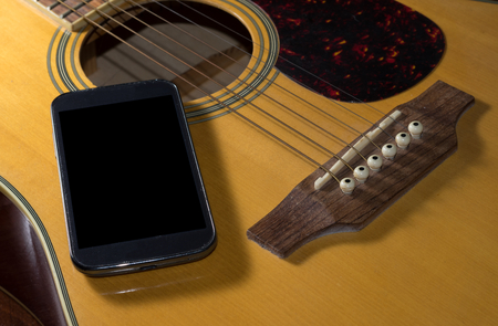 Smart phone on acoustic guitar.の写真素材