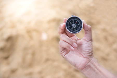 Compass in woman hand with sand background.の写真素材