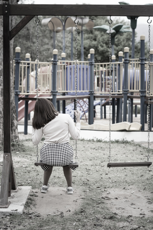 Lonely woman sitting on swing,vintage filtered.の写真素材