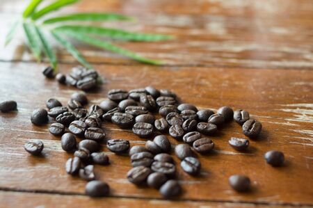 Black coffee beans with green leaf on table.の写真素材