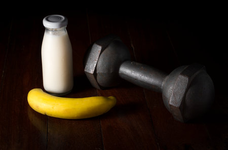 Milk bottle with banana and metal dumbbell.の写真素材