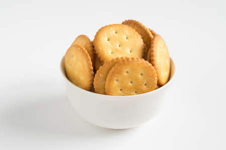 Cookies or crackers in brown bowl on white background.