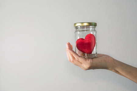 Woman holding red heart in glass bowl.の写真素材