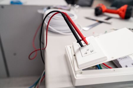 Digital multi meter to test measure the voltage at the power outlet on desk with drill and toolsの写真素材