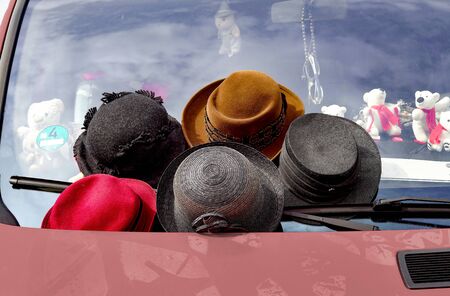 Women's flea-market hats are for sale on a windshield of a car