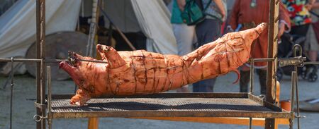 Grilled whole pig on a skewer. Traditional German food at festivals.の写真素材