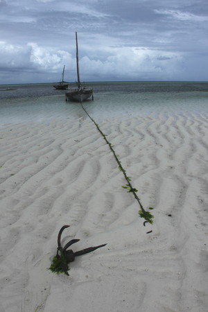 Wooden boat anchored in the sand with storm clouds in the backgroundの写真素材