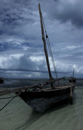 Wooden boat moored in the shallows with storm clouds in the background