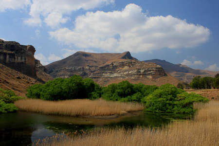 Country scene with pond, mountain, trees and cloudsの写真素材