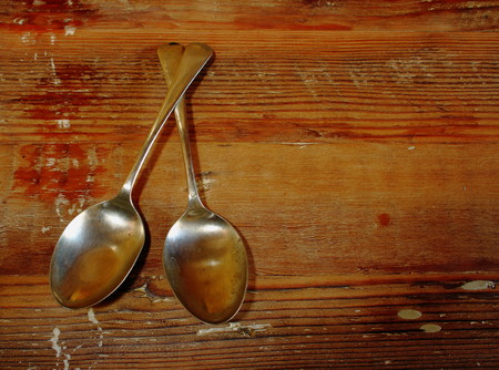 Two copper spoons on a textured wood backgroundの写真素材