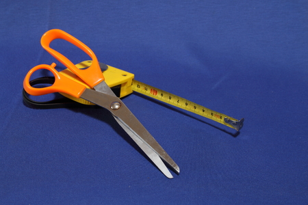 Orange scissors and yellow measuring tapeの写真素材
