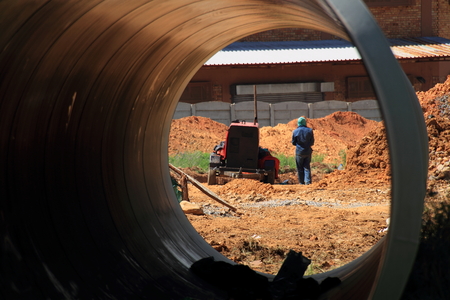 Civil works - generator and worker seen through a large pipe on a construction siteの写真素材