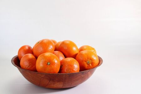 Fresh clementines in a wooden bowl on a white backgroundの写真素材