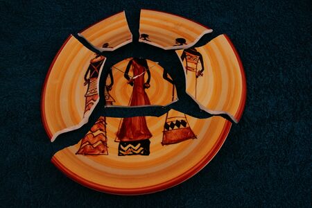 A broken ceramic dinner plate on a dark backgroundの写真素材