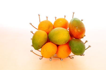 A bowl of green and orange fruit against a white background in landscape formatの写真素材