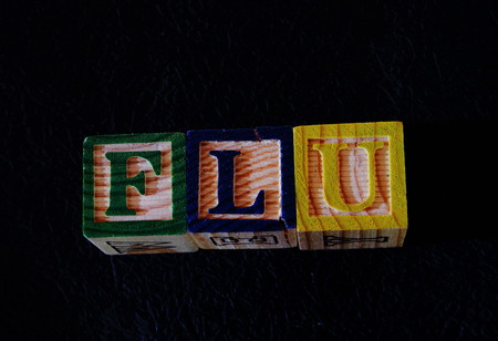 The term flu displayed visually on a black background using colorful wooden toy blocks in landscape...