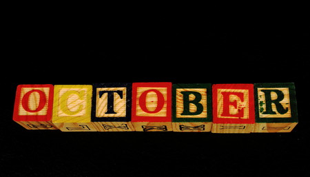 The term October visually displayed on a black background in landscape format using colorful wooden blocksの写真素材