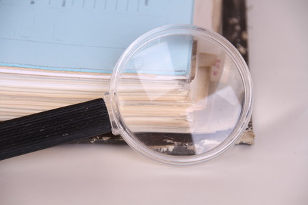 File with documents and a magnifying glass on a white background with copy spaceの写真素材