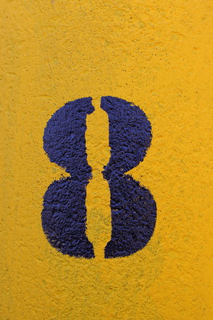 The number eight stenciled in black on a yellow surface in portrait format with copy spaceの写真素材