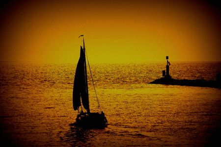 Yacht under sail leaves harbor at sunrise in landscape format with copy spaceの写真素材