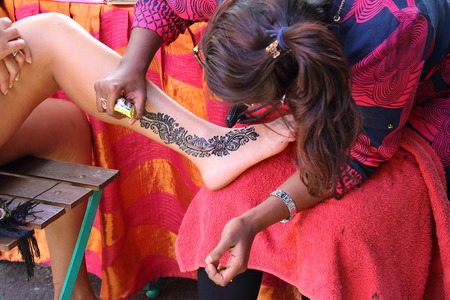 Port Louis, Mauritius - unidentified street artist does henna body painting for a customer at the Le Caudan Waterfront in the cityのeditorial素材