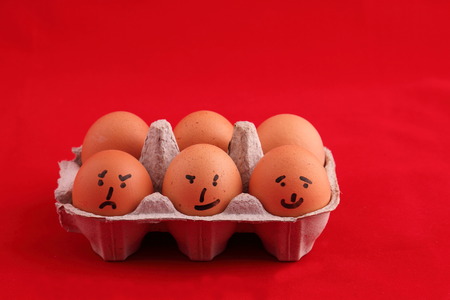 Eggs with comical faces in landscape format with copy space on a red backgroundの写真素材
