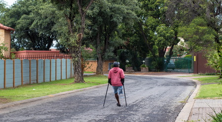 Johannesburg, South Africa - unidentified physically disabled man on crutches struggle through the streets of the city, image in landscape formatのeditorial素材