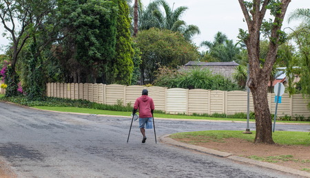 Johannesburg, South Africa - unidentified physically disabled man on crutches struggle through the streets of the city, image in landscape formatのeditorial素材
