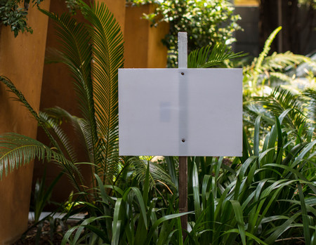 Blank white signboard to insert an own individual message on in a garden setting image in landscape format with copy spaceの写真素材