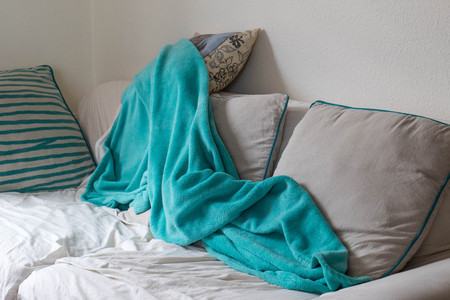 Untidy couch with a crumpled blanket that was used for a nap image in landscape format with copy spaceの写真素材