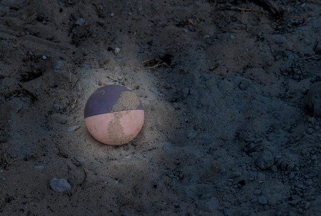Abandoned child's toy ball in dappled sunlight on a sandy patch image with copy spaceの写真素材