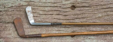 Two vintage golf clubs with hickory shafts isolated outdoors image with copy space