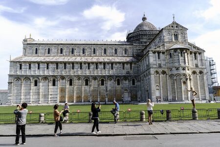 Young tourists posing in front of the cathedral in Pisa, Italyの写真素材