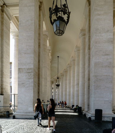 Young women strolling under the arches of St. Peter's Square in the Vatican State