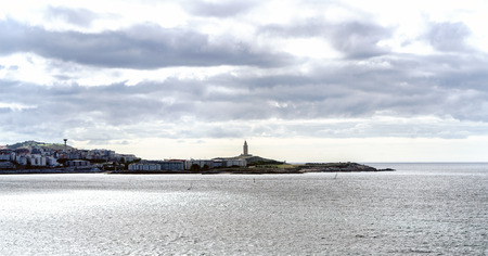 View of the coast of the city of La Coruna on the coast of Galicia (Spain). On the right the lighthouse called "Torre de Hercules", the oldest in Europe. Sky with clouds with sun reflectionsの写真素材