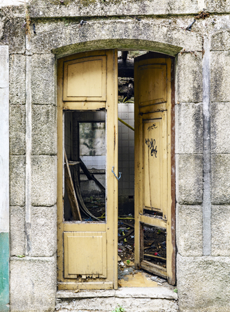 Broken yellow wooden door in an abandoned stone house with the interior completely demolishedの写真素材