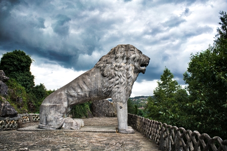 Betanzos, Galicia, Spain, August 25, 2017: Large sculpture of a lion sitting with a very cloudy sky, threatening rain. Park of the brothers Naveira, betanzos, Galicia, Spainのeditorial素材