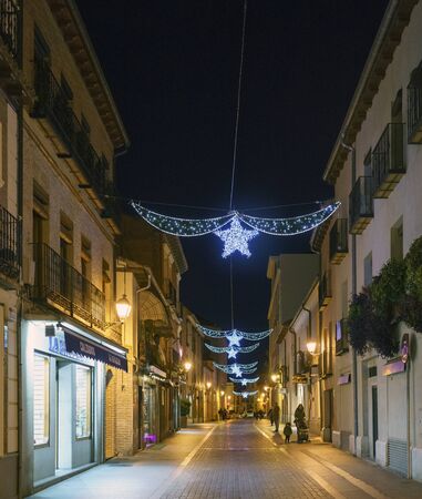 Alcala de Henares, Madrid, Spain / December 1, 2017: Night shot of a street in the center of town with white Christmas lights with a star and people walkingのeditorial素材