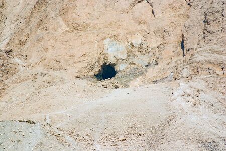 Close-up of the entrance of a tomb excavated on the side of a mountain of some personality of the ancient Egyptian empire with the entrance closed by an iron gate and another entrance with a caveの写真素材