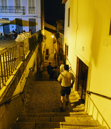Coimbra, Portugal, August 13, 2018: Night view of a narrow narrow cobblestone alley with steep stairs and tourists going up and downのeditorial素材