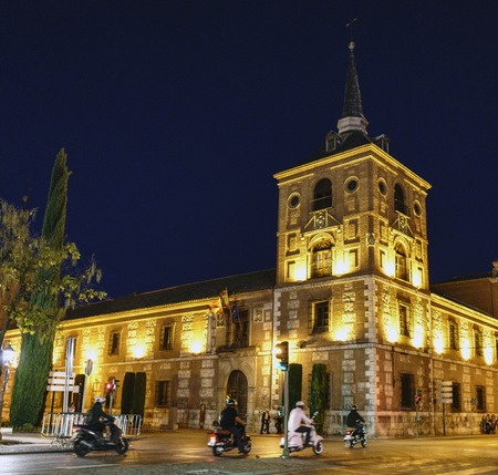 Night photo at slow speed with motorcycles passing and bright lights illuminating the facade of the convent school of San Agustin of the 16th century in Alcala de Henares (Spain)の写真素材